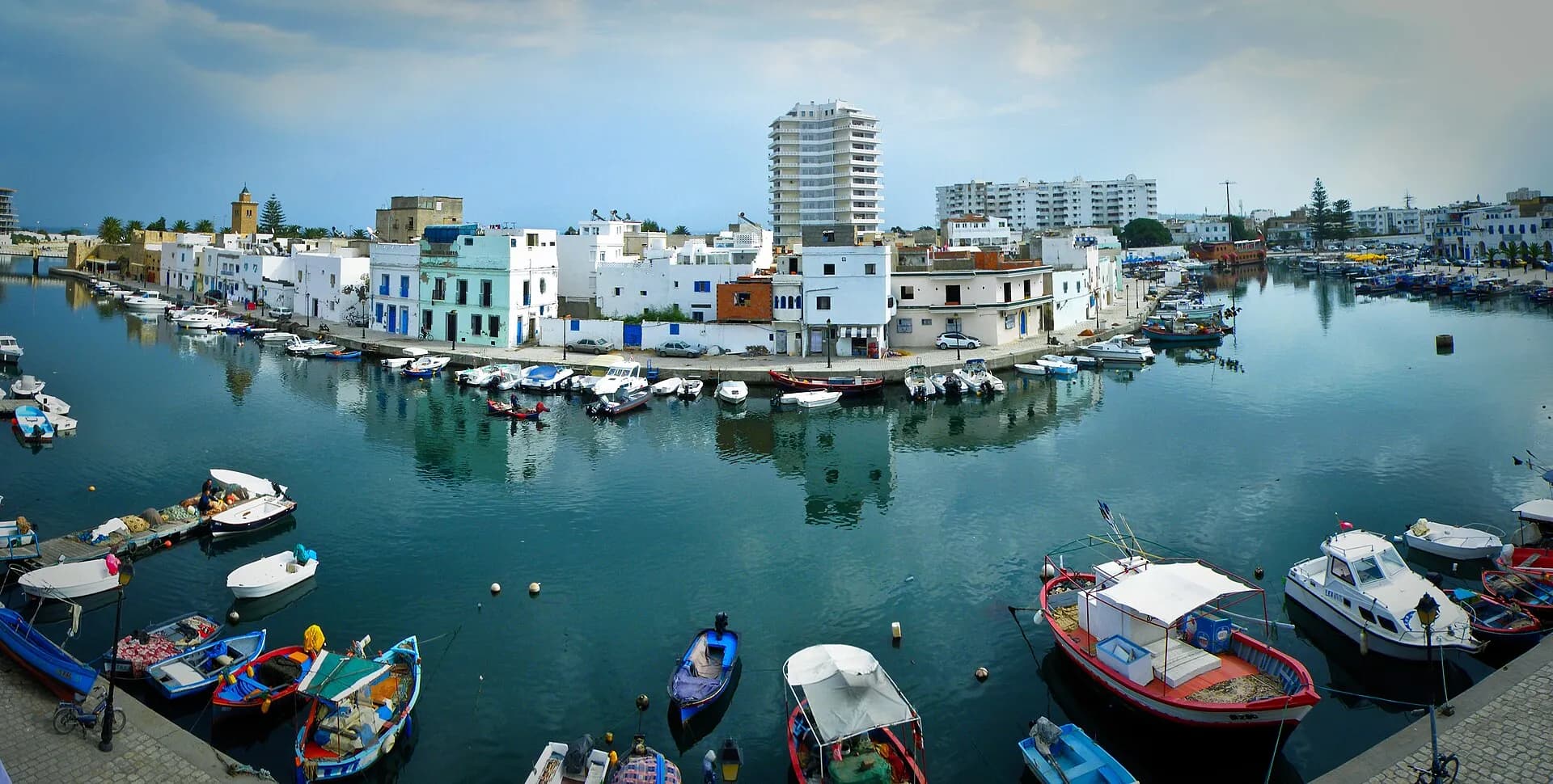 Le vieux port de Bizerte au coucher du soleil, avec ses barques colorées et la kasbah en arrière-plan